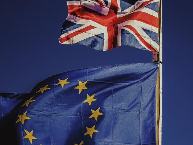UK flag and EU flag against a blue sky