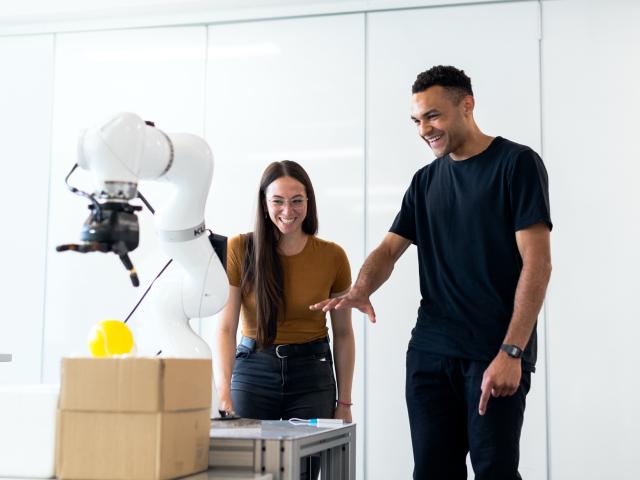 A man and woman standing by a robotic piece of machinery