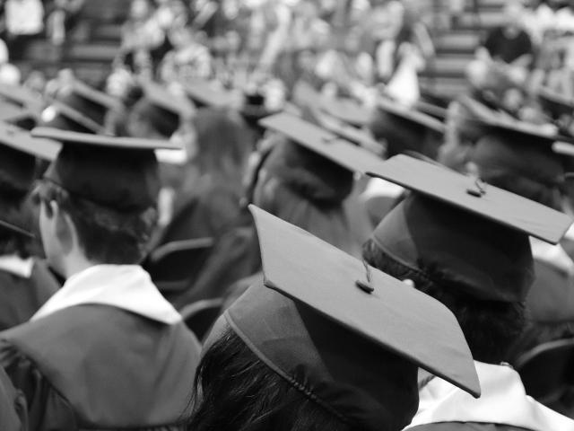 Black and white image of crowd of people in graduation robes
