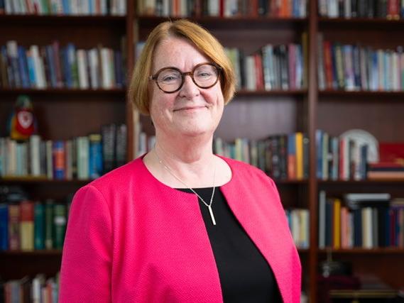 A photo of Professor Elwen Evans standing in front of bookshelves