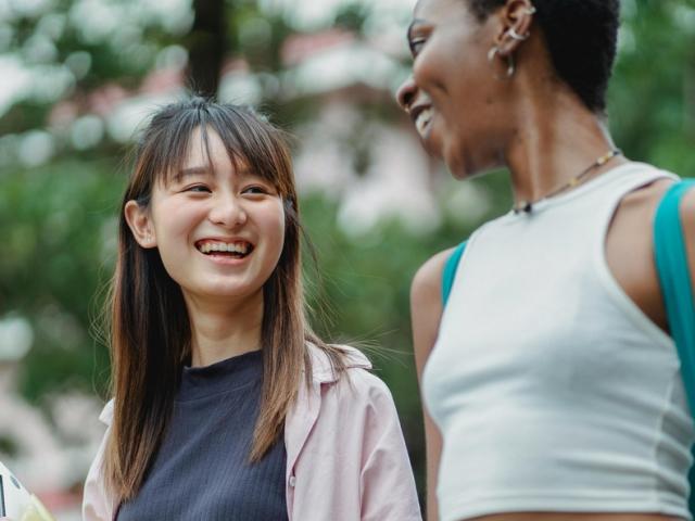 Two women walking outdoors smiling and talking to each other