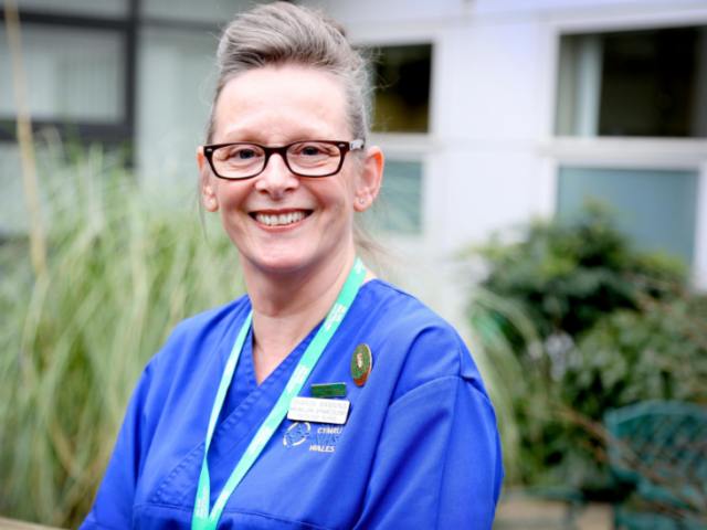 A photo of Sharon smiling and wearing nursing scrubs
