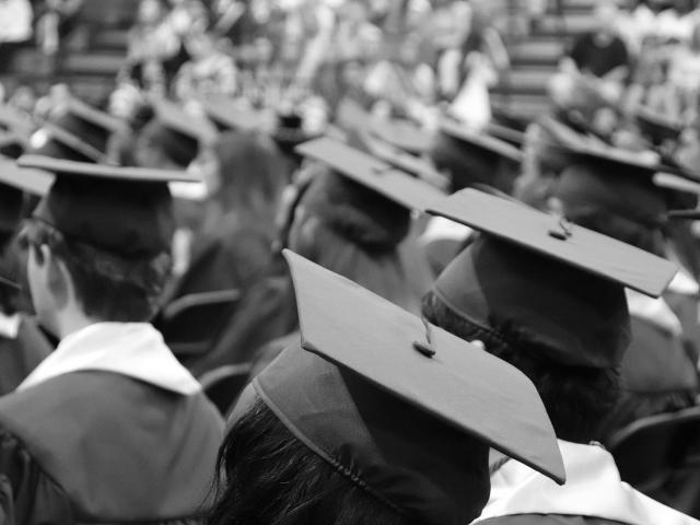 A black and white photo of a crowd of people in graduation robes